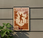 a sign with the word "SLACKLINING" on it, along with a silhouette of a person walking on a tightrope. The sign is mounted on a wall, and there is a plant to the left of the sign.