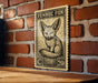 a wooden surface with a framed illustration of a Fennec fox on it, mounted on a brick wall.