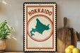A vintage-style sign with the text "Hokkaio" and a map of Japan, placed on a wooden shelf next to a potted plant and a wooden cutting board.