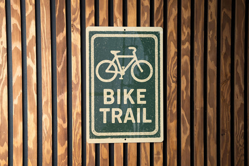A green and white sign with a bicycle symbol is mounted on a wooden wall.
