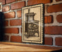 A vintage-style metal sign depicting an old-fashioned stove is mounted on a brick wall.