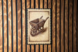 A wooden sign with a picture of a wheelbarrow is displayed against a wooden background.