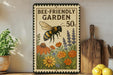 A vintage-style metal sign with a bee and flowers, advertising a "Bee-Friendly Garden 50¢" on a shelf with kitchen utensils and lemons.