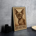 A wooden frame with a printed image of a cat, labeled "DEVON REX", is displayed on a table next to some black camera lenses.