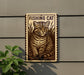a sign with a cat illustration, mounted on a wall next to a plant.
