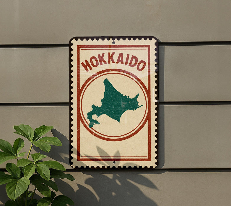 A sign with the word "Hokkaido" on it, featuring a map of the island, is mounted on a wall next to a plant.