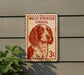 A Welsh Springer Spaniel dog is depicted on a postage stamp-like sign, mounted on a wall.