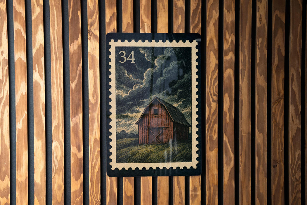 A wooden wall with a framed image of a barn in the center.