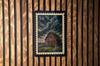A wooden wall with a framed image of a barn in the center.