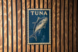 A blue sign with a fish illustration is mounted on a wooden wall.