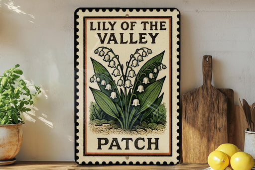 A framed sign with the text "Lily of the Valley PATCH" is displayed on a shelf next to a wooden cutting board and a potted plant.