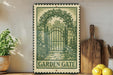 a vintage-style metal sign with a garden gate design, placed on a wooden shelf next to a potted plant and a wooden cutting board.
