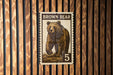 A brown bear stamp with the number 5 on it, displayed on a wooden wall.