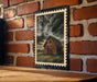 A framed illustration of a red barn is displayed on a brick wall, with a black border and the number 34 printed on the top left corner of the frame.