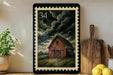 A framed illustration of a wooden barn with a stormy sky in the background, placed on a shelf next to a wooden cutting board and a potted plant.