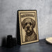 A framed illustration of a Boxeroodle dog is displayed on a table, with a stack of black camera lenses and a white plate nearby.