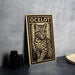 a wooden stamp with a cat illustration on it, placed on a table next to some black camera lenses.