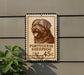 A brown and white Portuguese sheepdog dog is depicted on a brown and white sign attached to a gray wall.