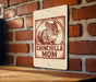 A sign featuring a chinchilla and the text "CHINCHILLA MOM" is displayed on a brick wall.