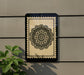 a decorative black and white floral pattern on a wall, with a plant to the left of the frame.