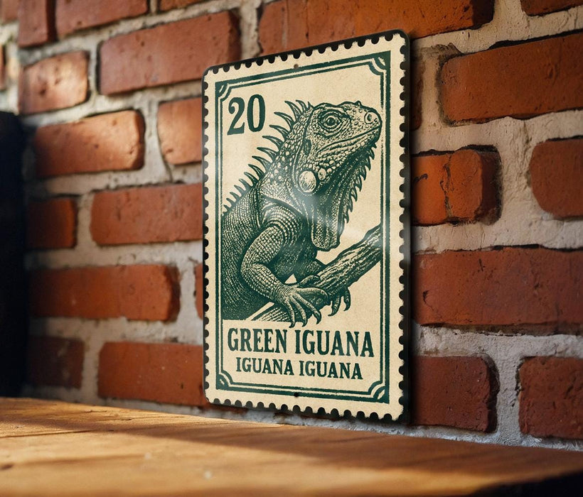 A green and white postage stamp featuring a detailed illustration of a green iguana is displayed on a brick wall.