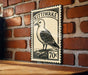 A vintage-style postage stamp featuring a black and white illustration of a bird, mounted on a brick wall.