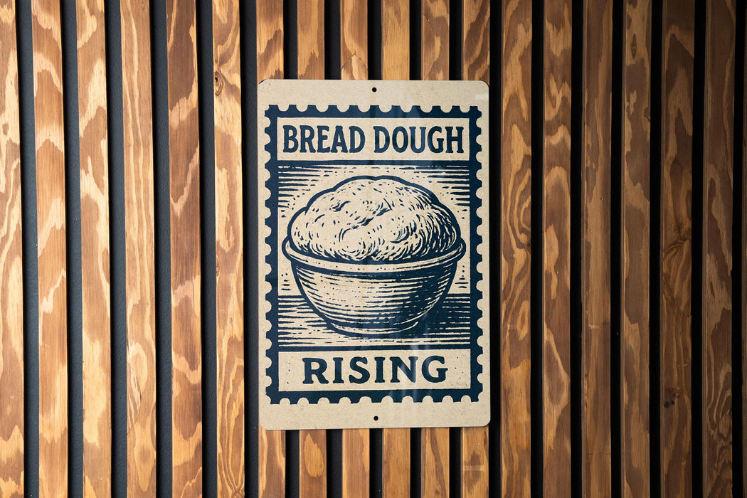 A sign with the text "BREAD DOUGH RISING" and an illustration of a bowl of dough, mounted on a wooden wall.
