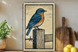 A framed illustration of a blue bird perched on a wooden post is displayed on a shelf, accompanied by a wooden cutting board, a potted plant, and some lemons.