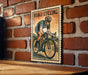 A vintage-style poster of a cyclist on a road, mounted on a brick wall.
