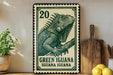 A green and white postage stamp featuring a detailed illustration of a green iguana, with the text "Green Iguana" and "Green Iguana" printed on it. The stamp is placed on a wooden surface, with a potted plant, a wooden cutting board, and some lemons nearby.