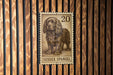 A metal sign featuring a drawing of a brown dog, specifically a Sussex Spaniel, mounted on a wooden wall.