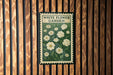 A vintage-style metal sign with a floral design, mounted on a wooden wall.