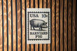 A metal sign with a black and white illustration of a pig, mounted on a wooden wall.