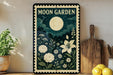 A framed poster of a moon garden with a large moon, flowers, and plants is displayed on a wall next to a wooden cutting board and a potted plant.