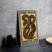 a wooden sign with a snake design, placed on a table next to some black camera lenses.