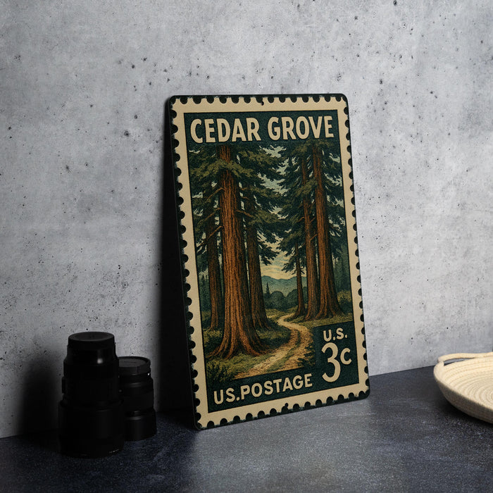 A vintage U.S. postage stamp featuring a forest scene, with a path leading through the trees, is displayed on a table next to some black camera lenses.