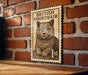 A British Shorthair cat is depicted on a wooden surface, with a British postage stamp featuring the cat prominently displayed.