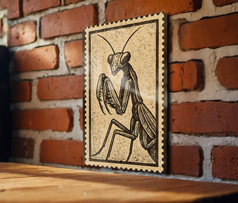 a wooden table with a framed illustration of a praying mantis on it, mounted on a brick wall.