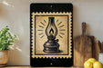 a black and white illustration of an oil lamp on a wooden surface, with a potted plant and a wooden cutting board visible in the background.