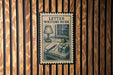 a letter writing desk with a lamp, books, and a typewriter, all depicted in a vintage-style illustration on a wooden wall.