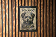 A black and white dog stamp with the text "POMAPOO" and "50c" printed on it, mounted on a wooden wall.