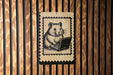 A wooden wall with a black and white illustration of a hamster sitting on a laptop computer.