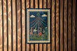 A framed illustration depicting a group of people dancing around a tall pole with colorful ribbons, set against a dark background.