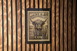 a wooden wall with a black and white cow stamp or label prominently displayed in the center.