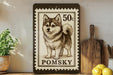 A framed image of a pomeranian dog, which appears to be a postage stamp, is displayed on a shelf next to a wooden cutting board and some lemons.