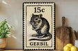 A black and white postage stamp featuring a mouse, with the text "15c" and "GERBIL" printed on it, placed on a wooden surface next to a wooden cutting board and some lemons.