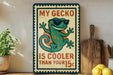 A vintage-style sign featuring a cartoon gecko wearing sunglasses, with the text "MY GECKO IS COOLER THAN YOUR 15¢" displayed prominently.
