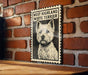A framed illustration of a white terrier dog is displayed on a brick wall.