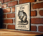 A black and white postage stamp featuring a mouse on a brick wall.
