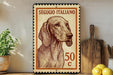 A framed Italian postage stamp featuring a dog's portrait, placed on a wooden surface next to a wooden cutting board and some lemons.